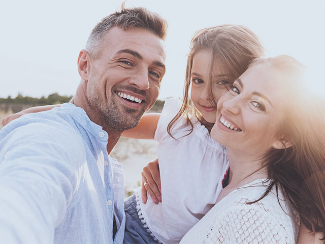 Young, happy family taking a selfie on the beach.